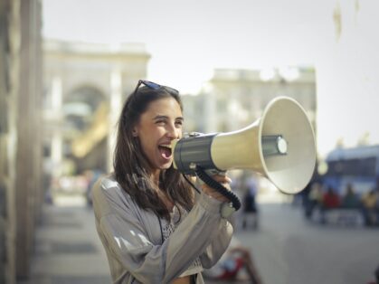 Cheerful young woman Talking into megaphone
