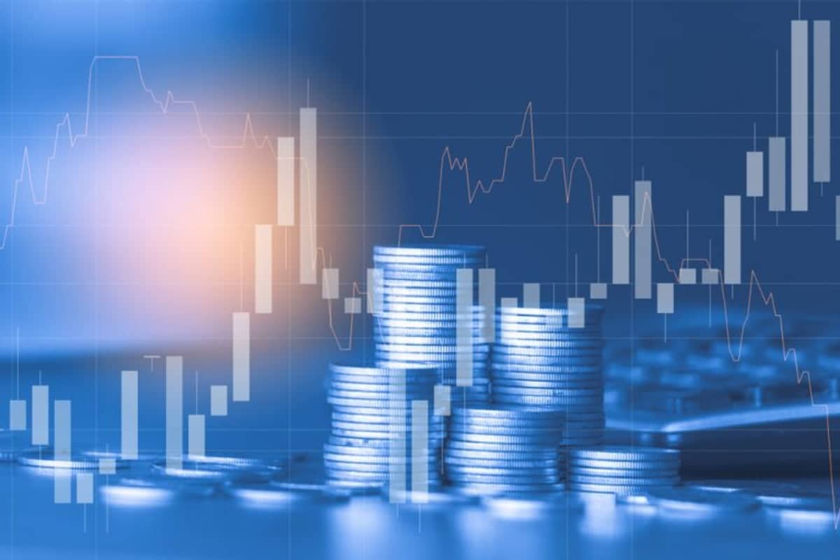 A financial concept image featuring stacks of coins in the foreground, illuminated with a blue hue. In the background, a glowing light and an overlay of stock market graphs and bar charts suggest economic trends or investment growth.image